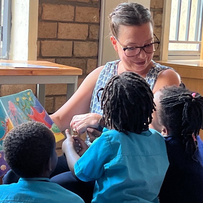 A visitor reading a picture book with Bright School children