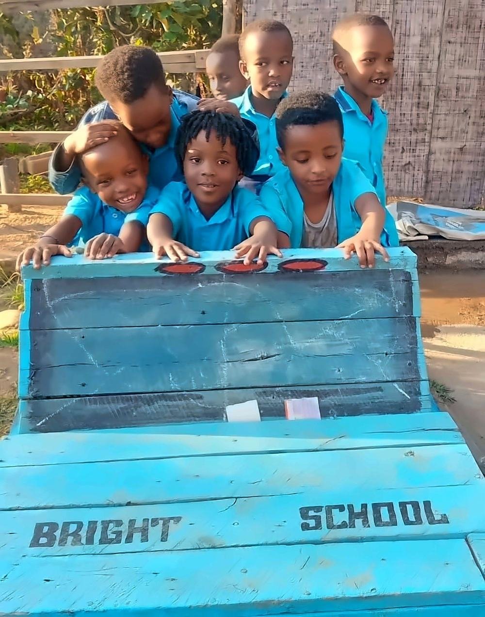 Young Bright School learners gathered around the painted Bright School bench