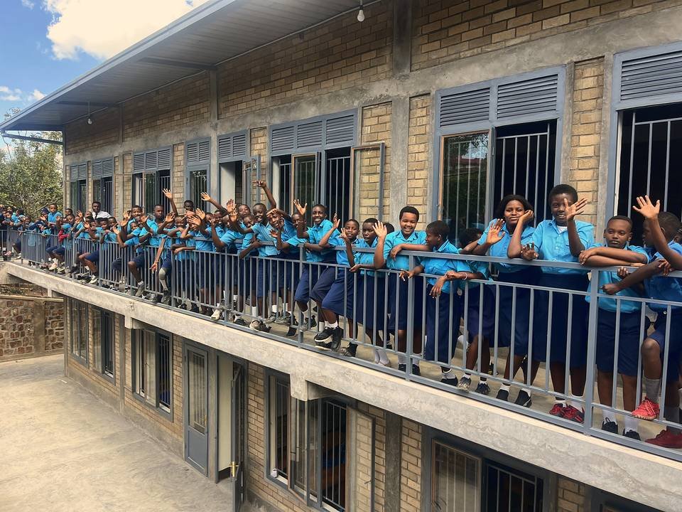 Bright School children lined along the balcony rail of the new building, waving