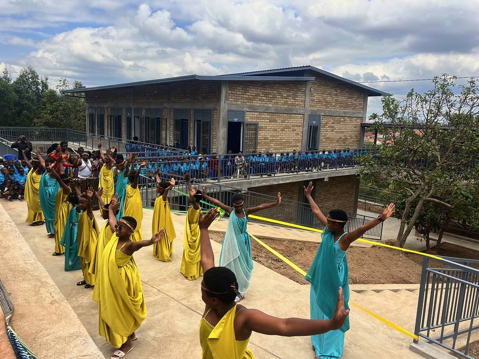 Dancers in yellow and teal costumes performing on the ramp beside the new Bright School building