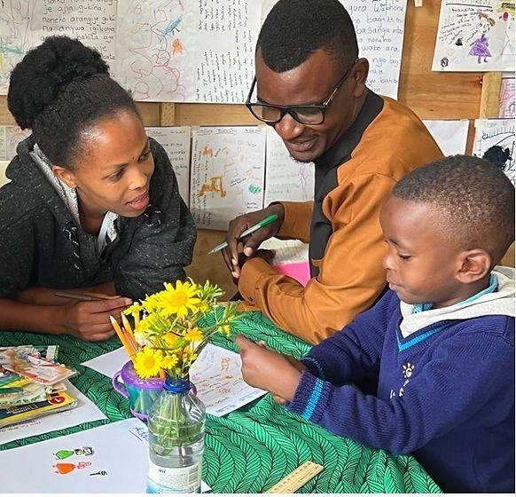 Two adults and a child working together at a classroom table