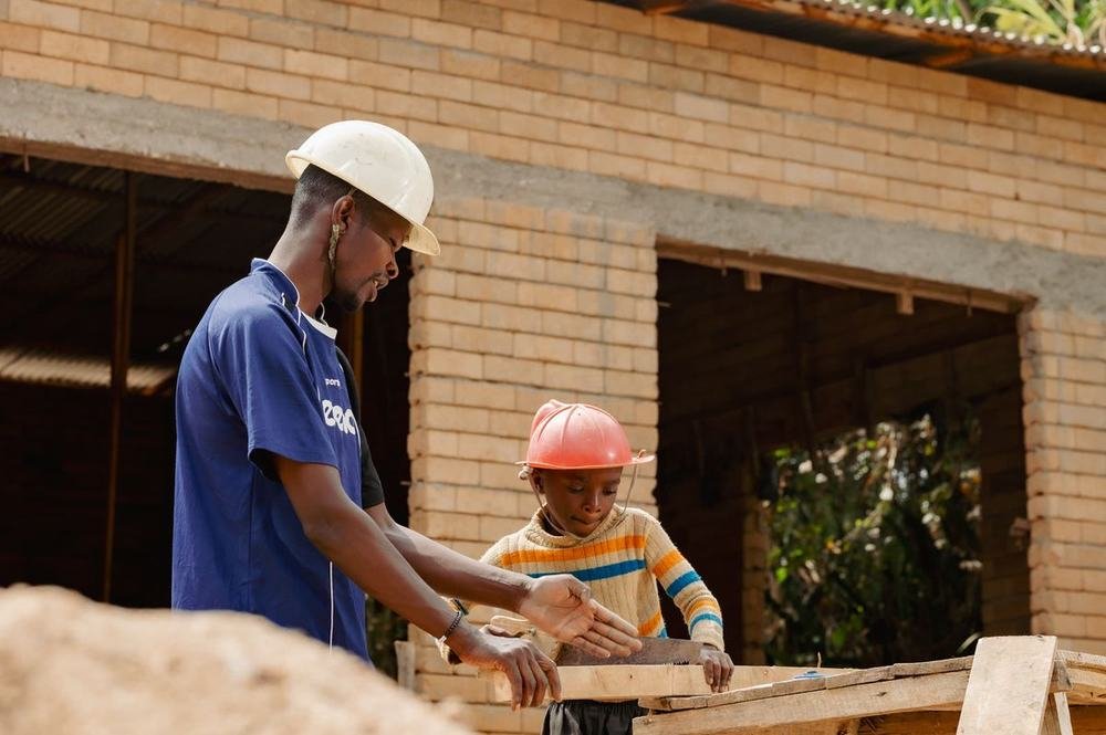 A Construction Club mentor guiding a learner using a handsaw
