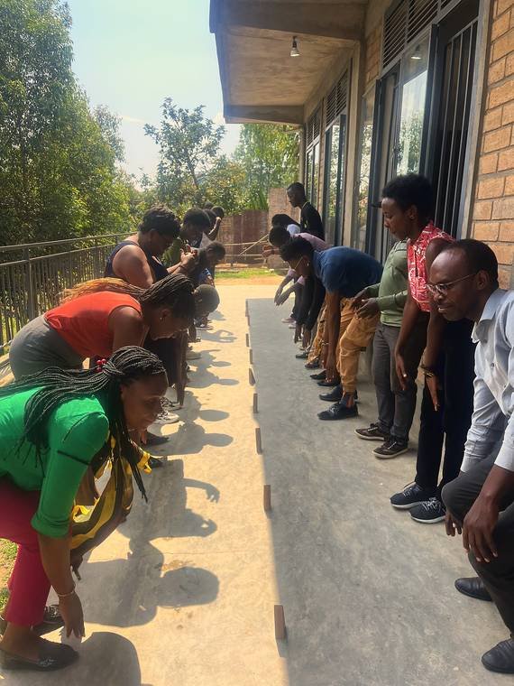 Teachers bent over a line of markers on the ground during a measuring activity