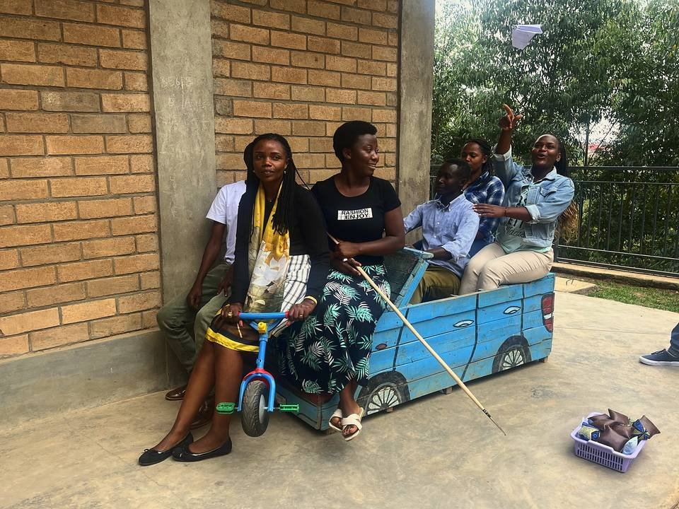 Teachers seated in a cardboard car prop, one throwing a paper plane, during a workshop activity