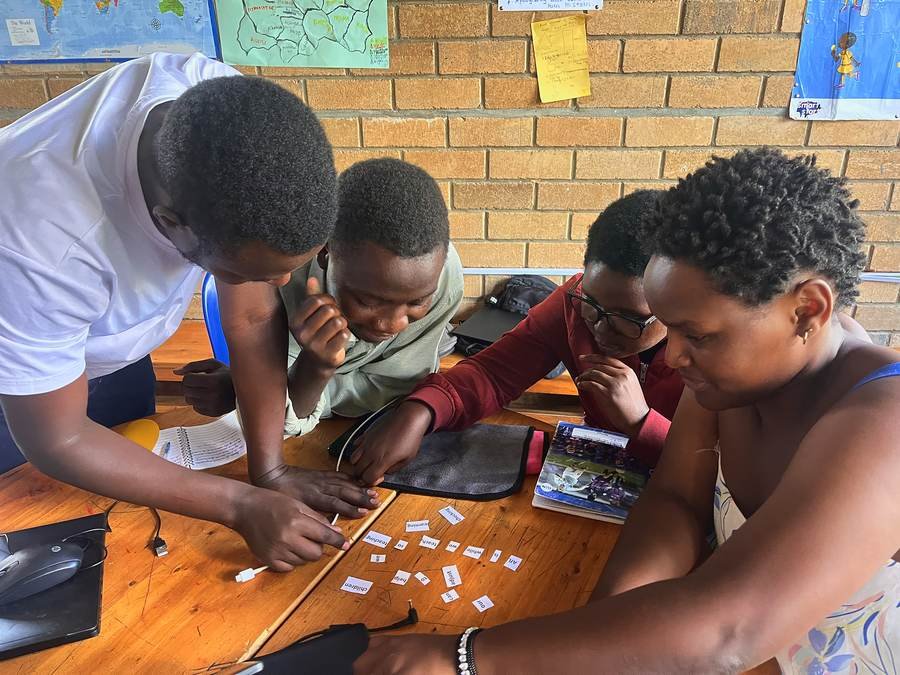 A facilitator and teachers leaning over a table of word cards