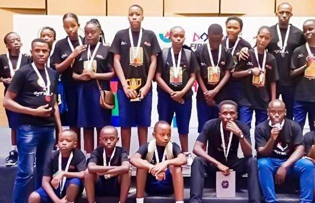 A robotics team with medals and trophies at a competition