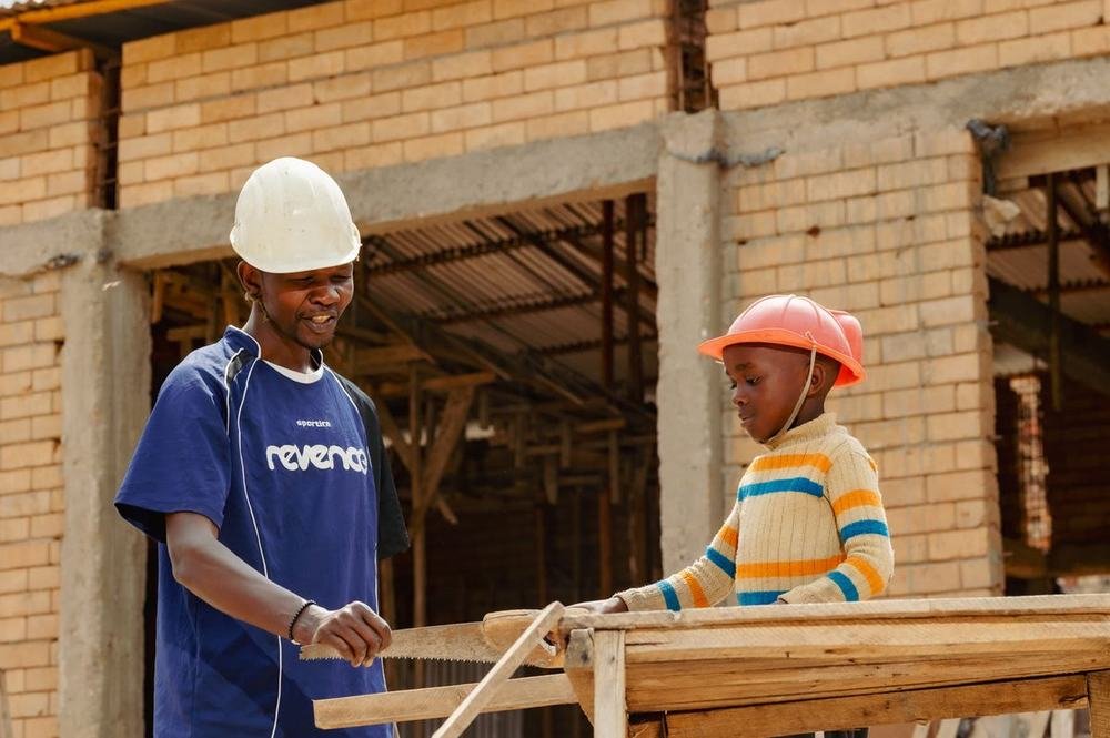 A Construction Club mentor working with a learner at a wooden sawhorse