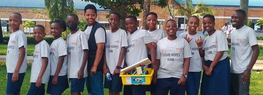 A robotics team in matching team shirts standing with their kit box