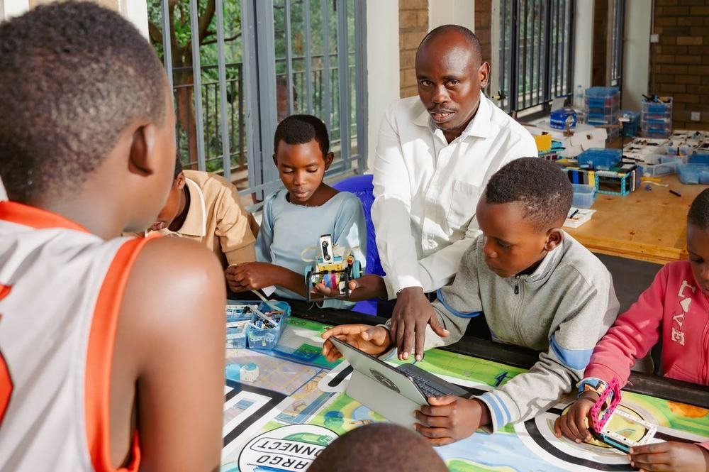 A facilitator guiding learners programming a LEGO SPIKE robot on a tablet