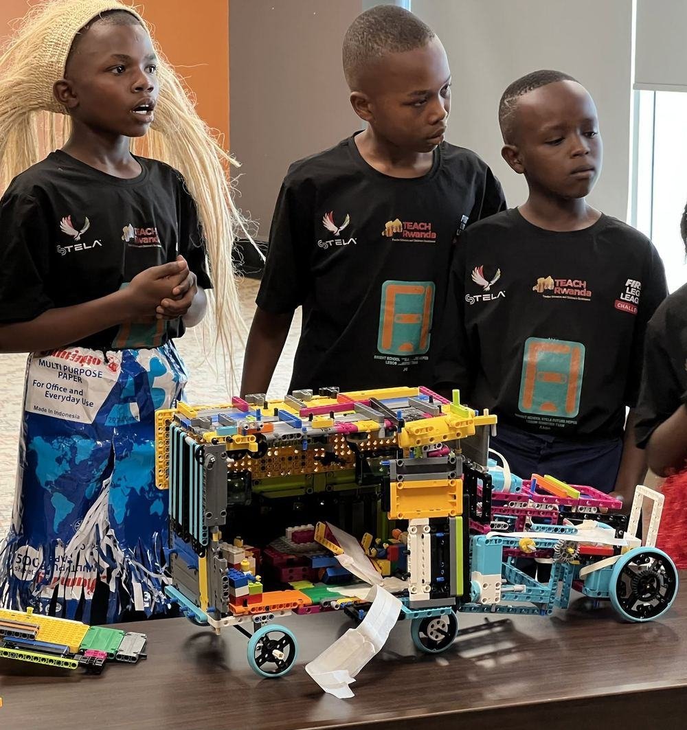 Three learners in STELA and FIRST LEGO League Challenge shirts presenting their robot