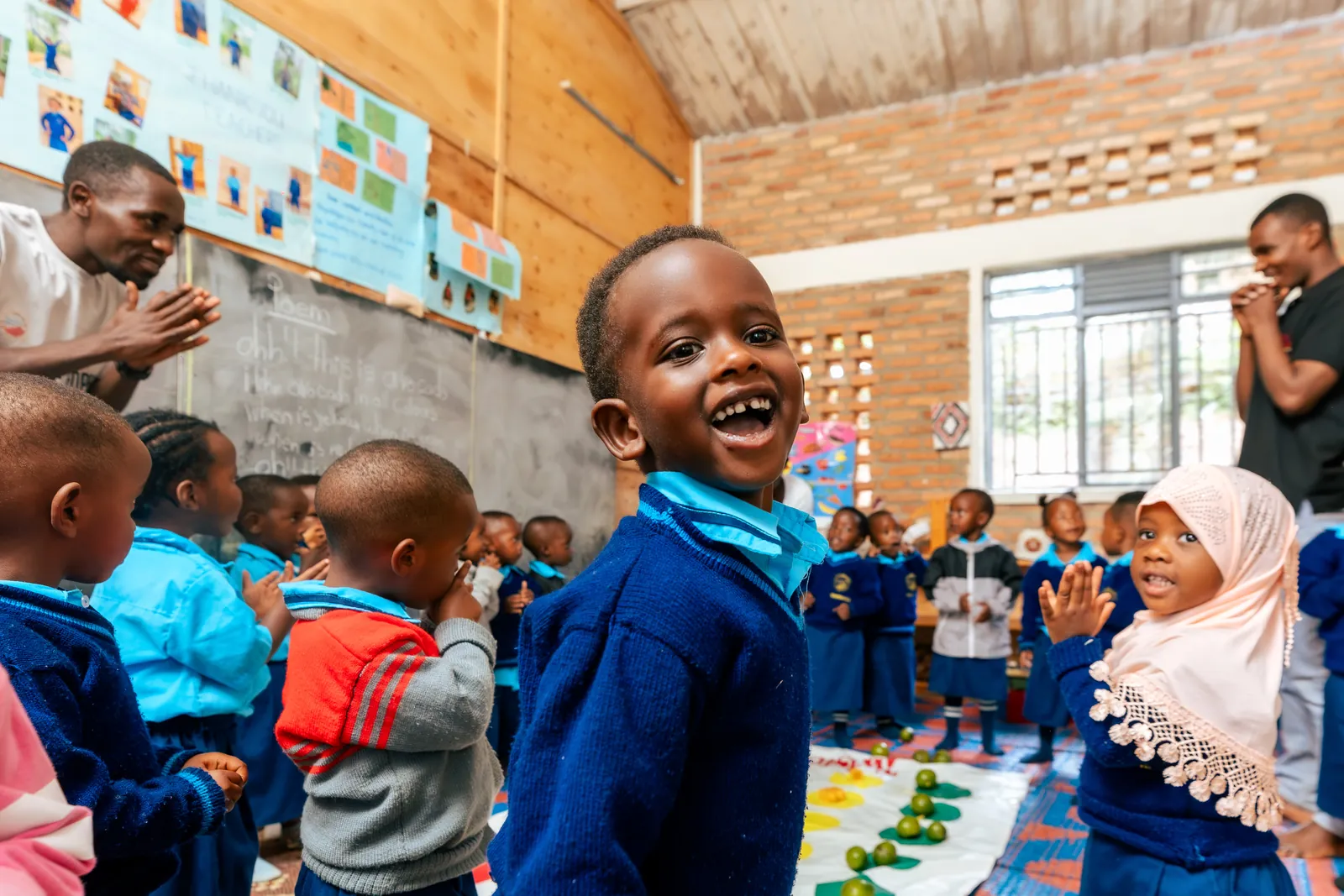 A boy laughing in a busy nursery classroom