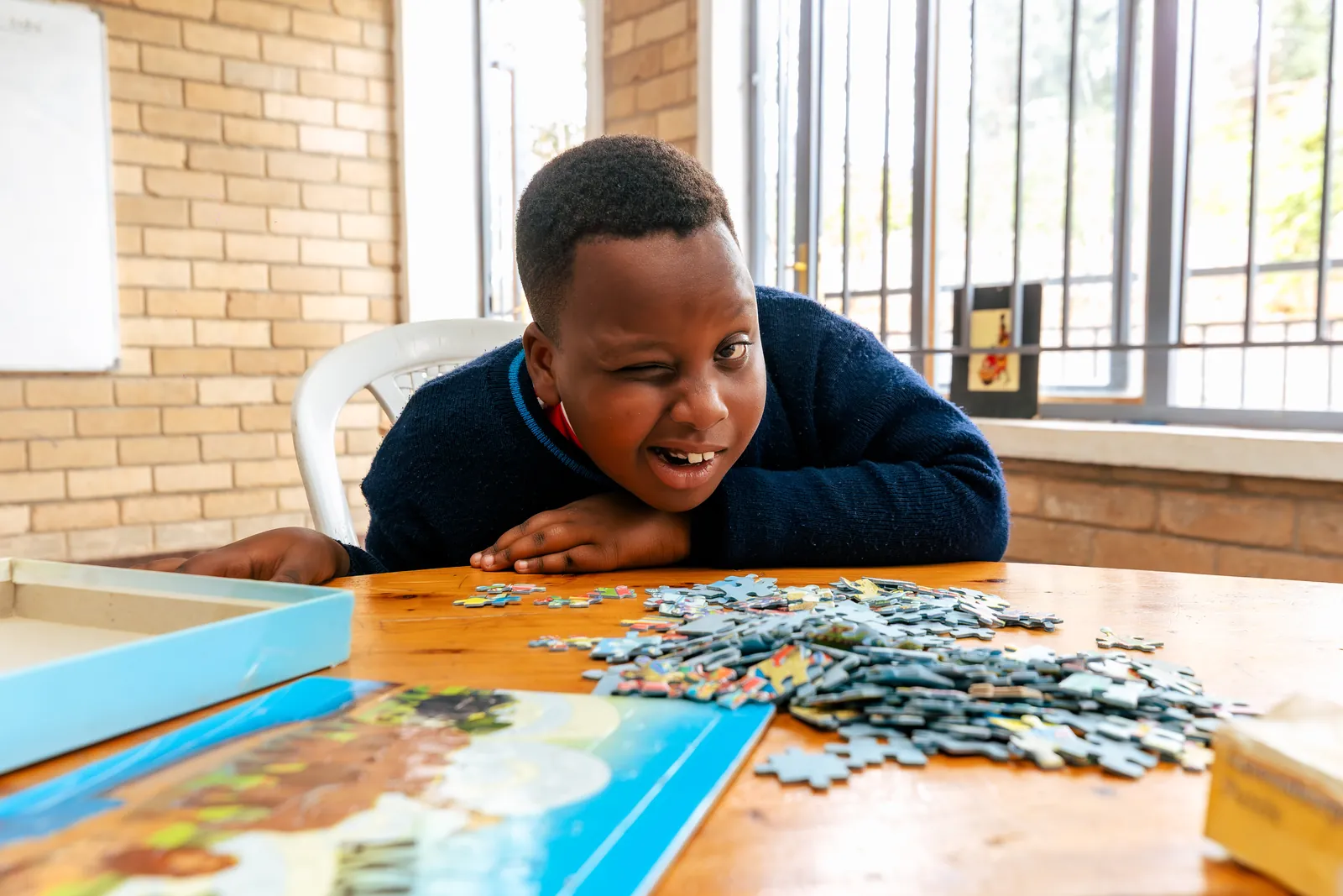 A boy smiling over a jigsaw puzzle on a table