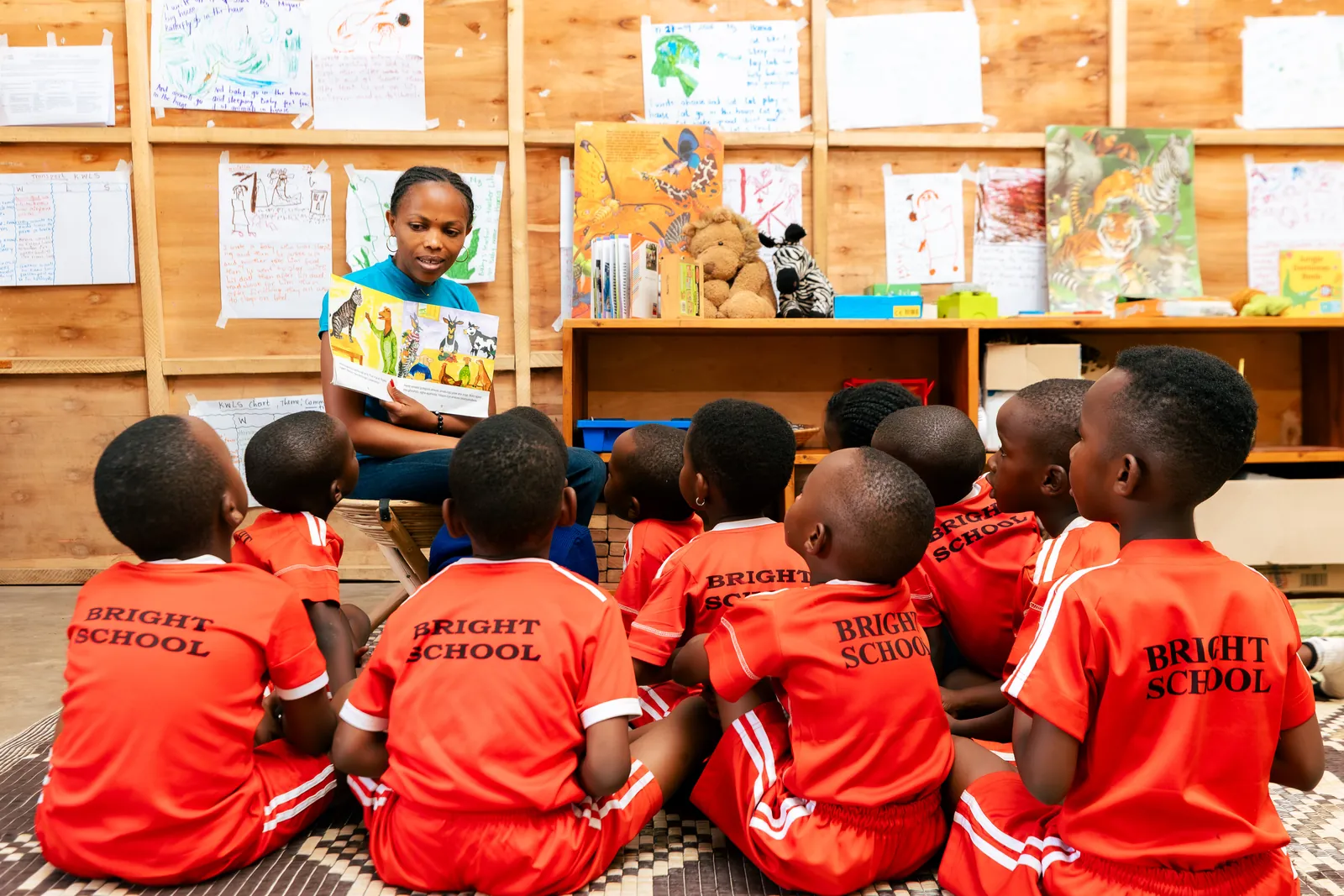 Children sitting on the floor listening as their teacher reads a picture book