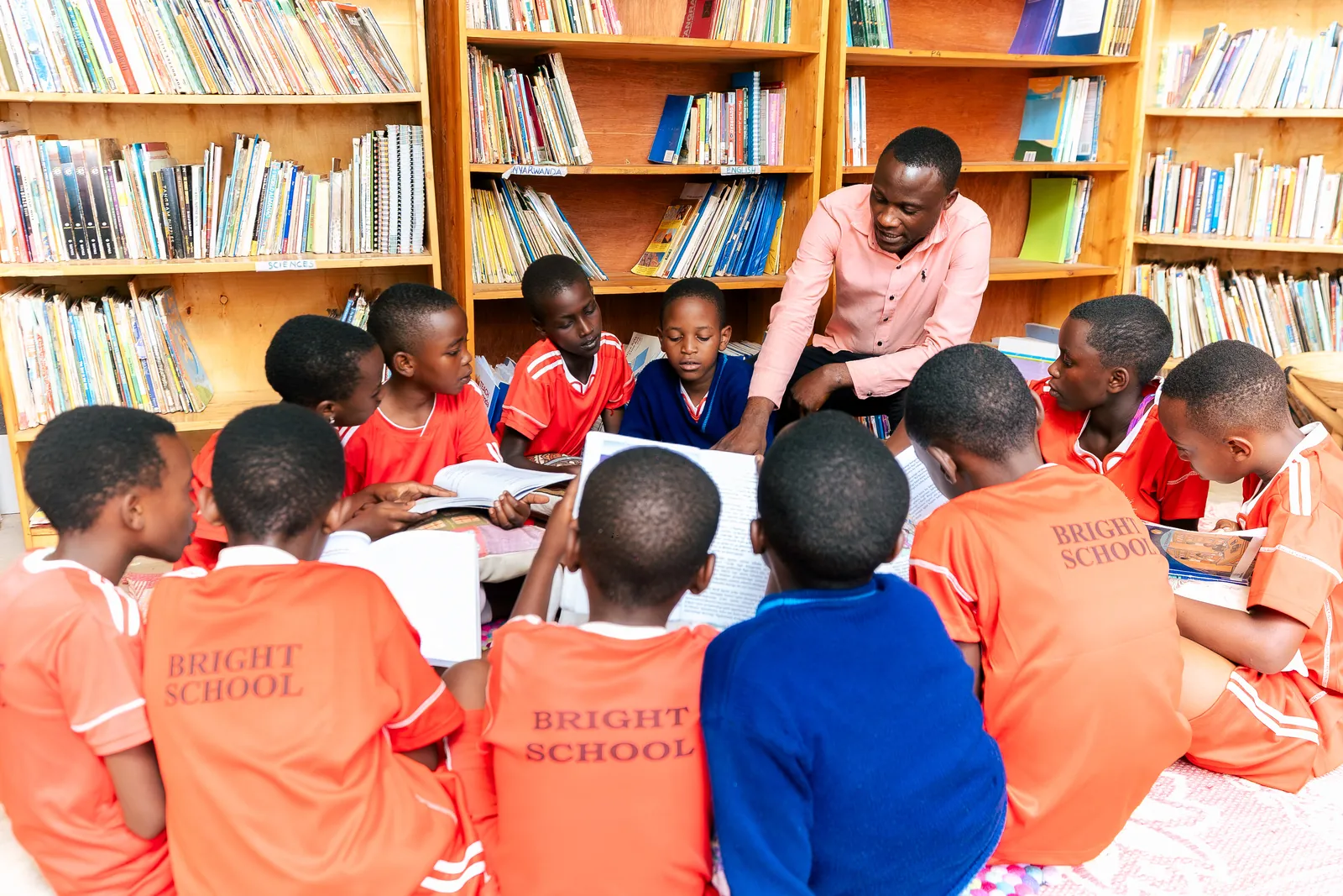 Children gathered on the floor around a shared book with a teacher