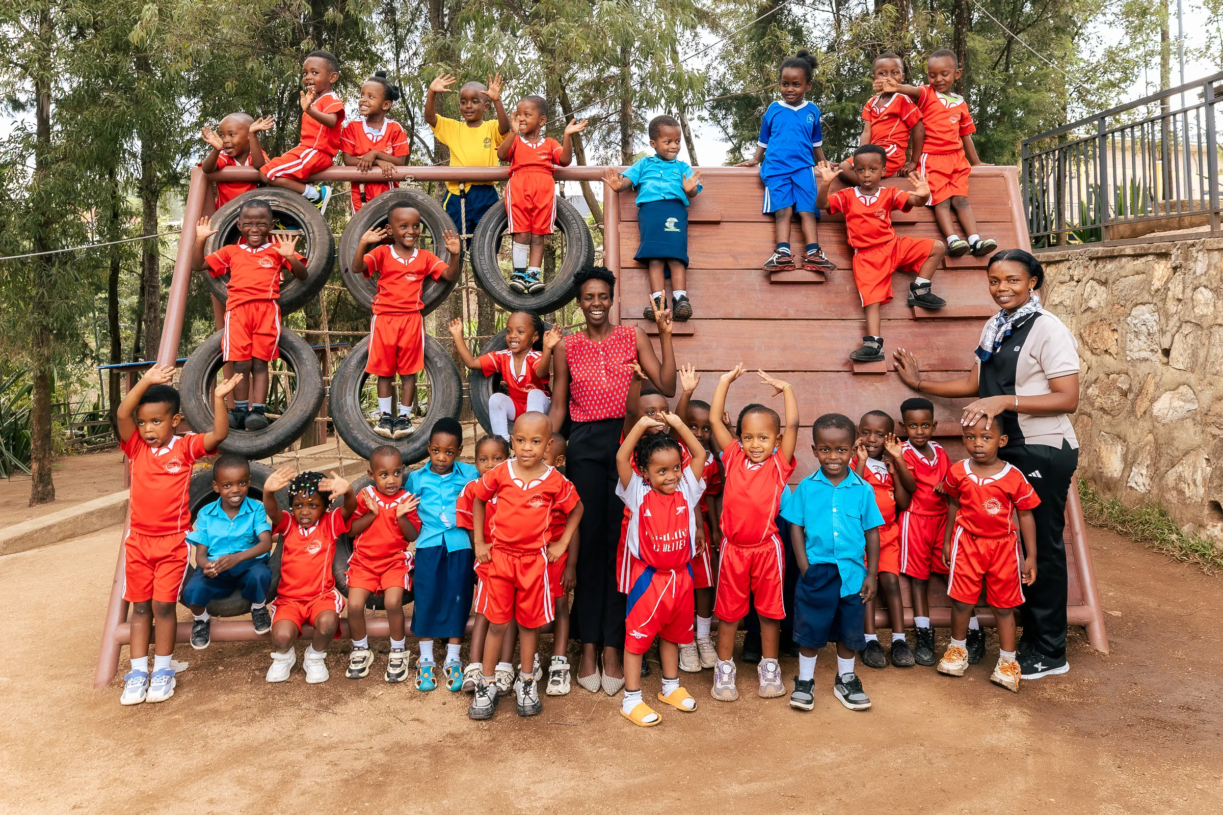 Bright School children in red and blue uniforms cheering on the climbing wall with their teachers
