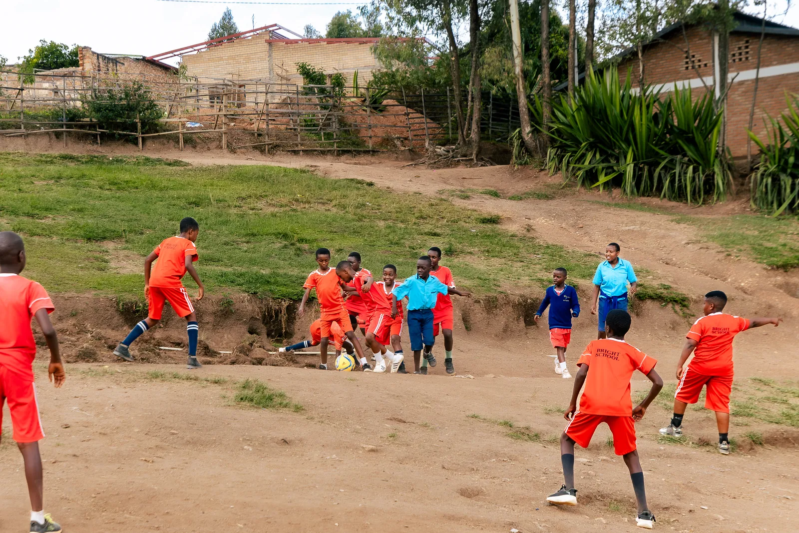 Children playing football on a hillside pitch