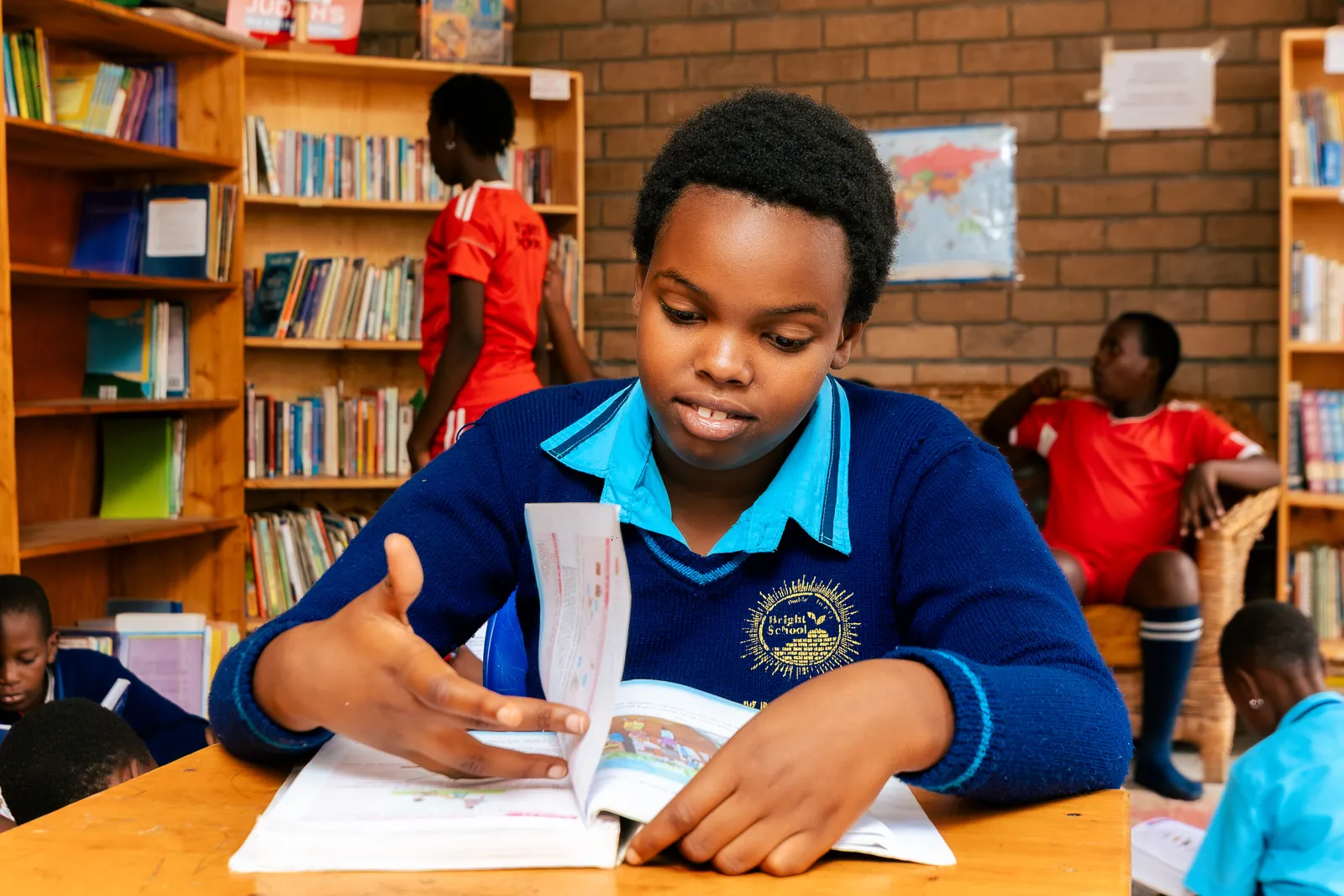 A girl in a navy jumper reading a book at a library desk