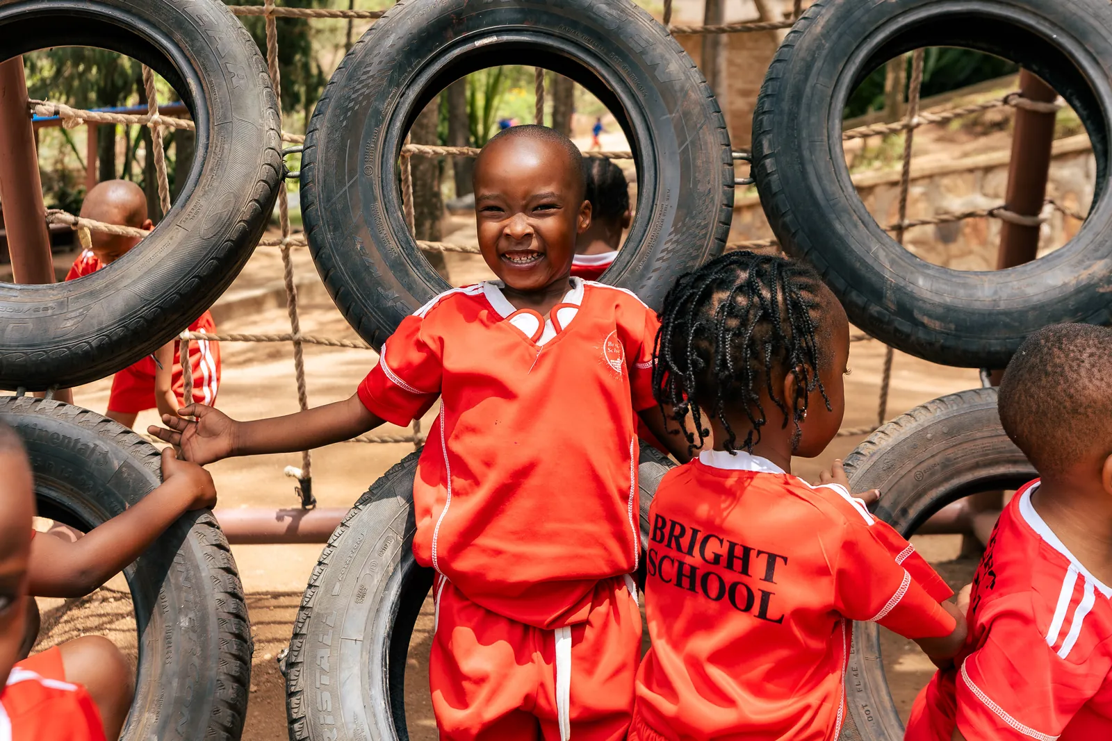 Two children laughing together on the playground tyre wall