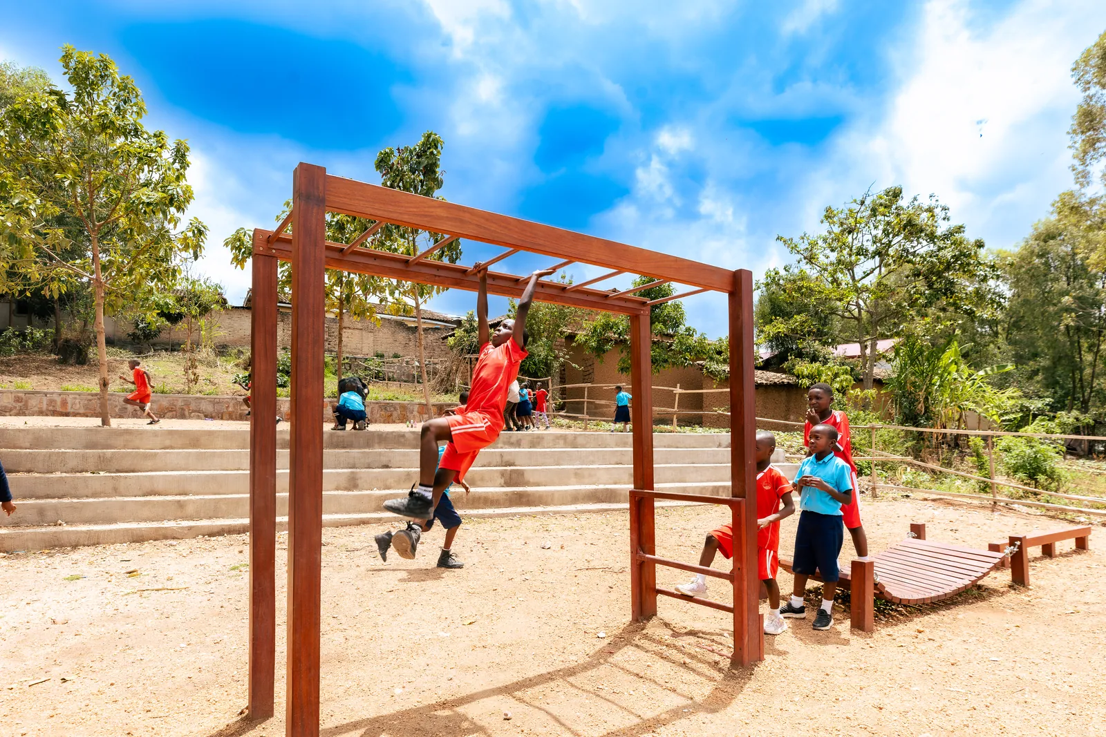 A child swinging on wooden monkey bars under a bright blue sky