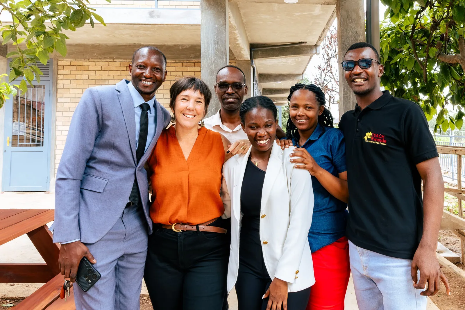 TEACH Rwanda team members standing together outside the school, smiling
